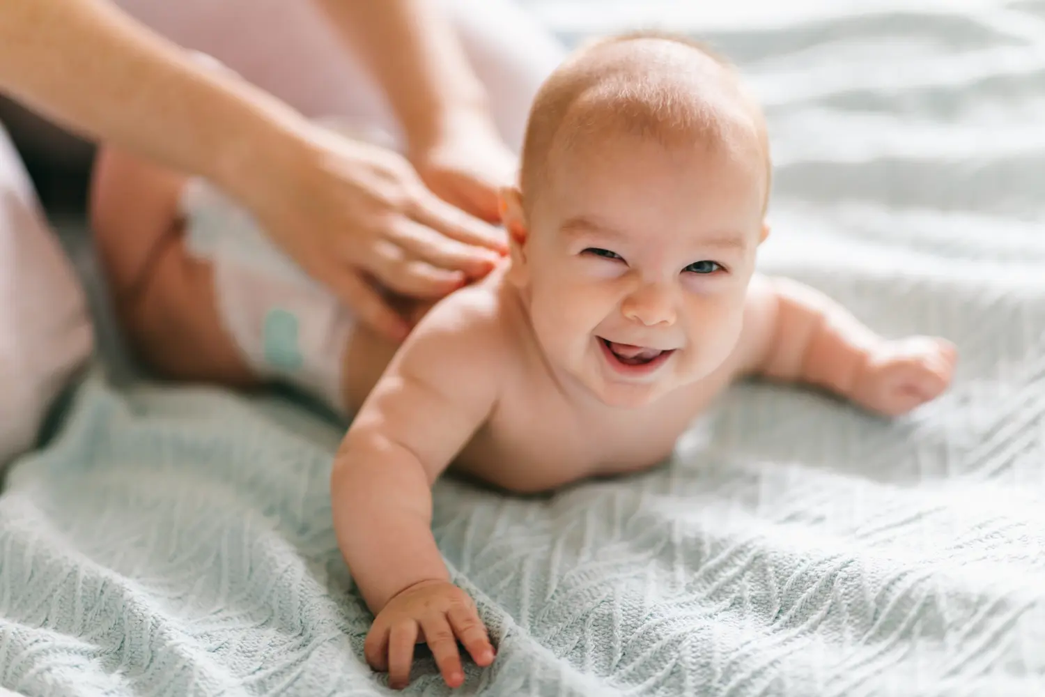 Massage für das Baby. Vier Monate altes Baby lächelt beim Turnen