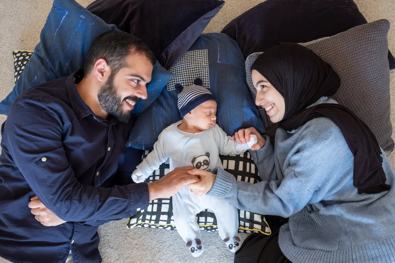 Arabisch-muslimische Eltern teilen einen zärtlichen Moment mit ihrer neugeborenen Tochter und strahlen Liebe und Freude in ihrem Zuhause aus.